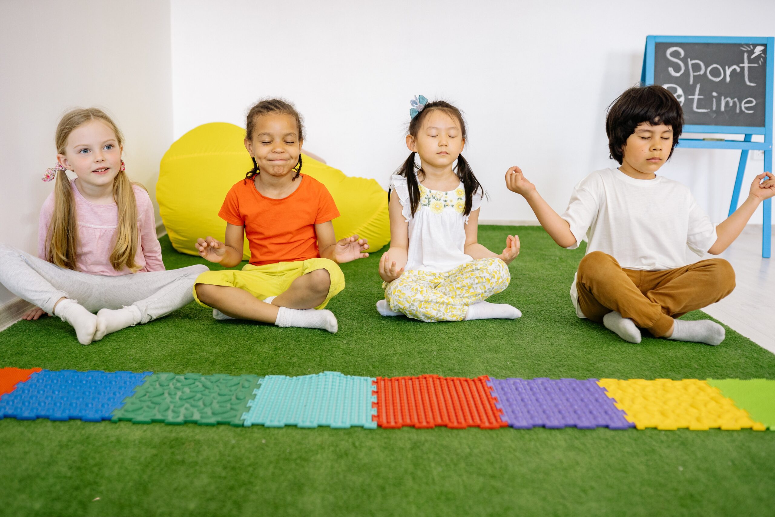 kids sitting on a green floor meditating